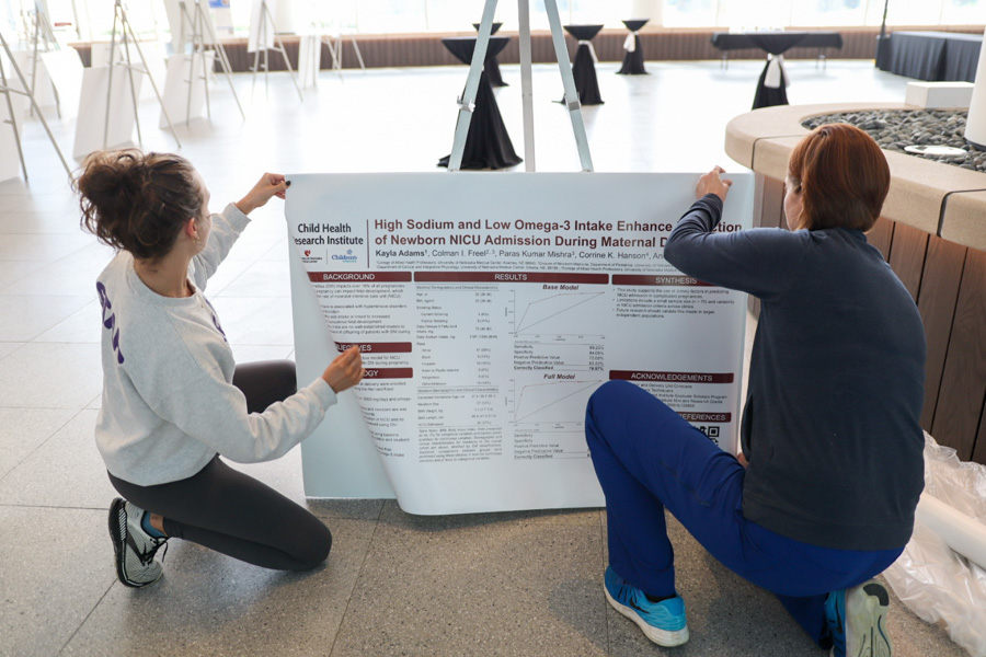 two people pinning up scientific poster