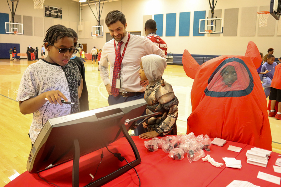 Children at science booth in Halloween costumes talking to man