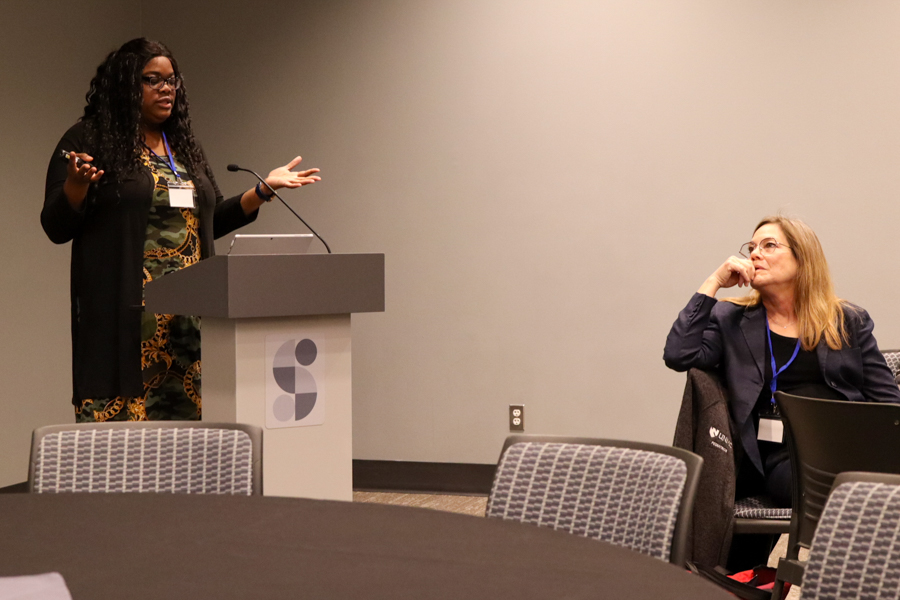 woman talking at podium with seated woman listening to her