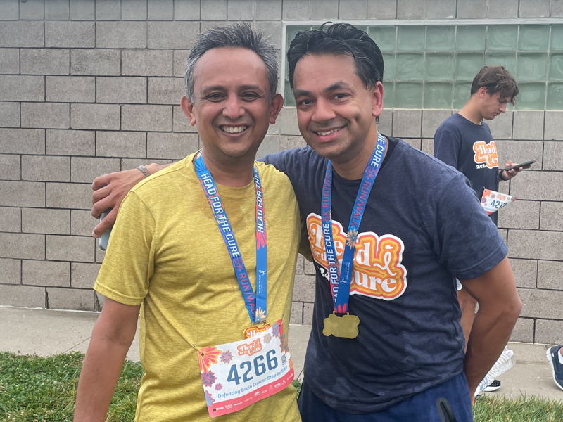 Two men pose at charity race with medals around their necks