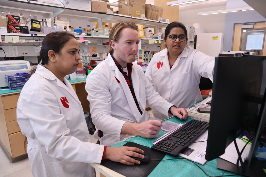 two women and a man in a scientific lab looking at a computer screen