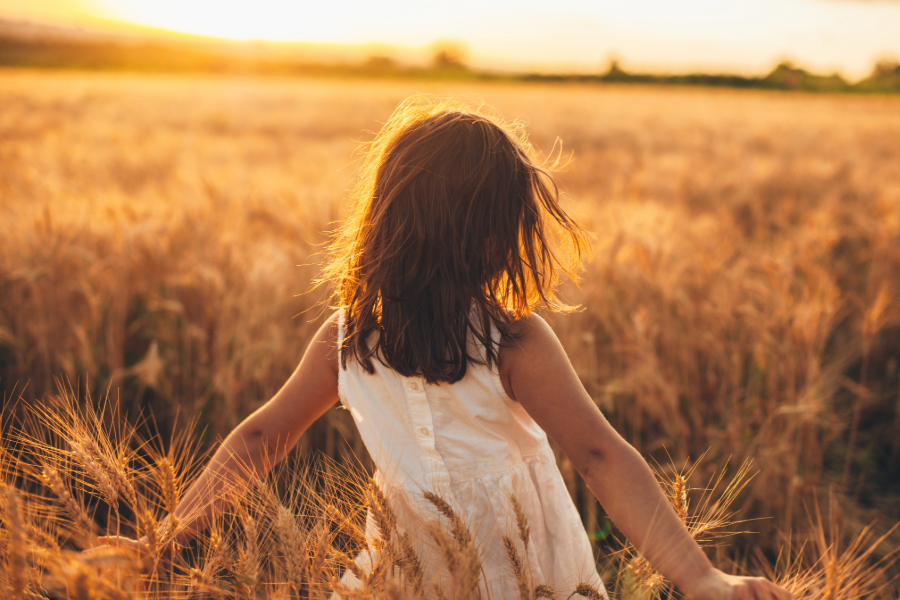 young girl walking through wheat field