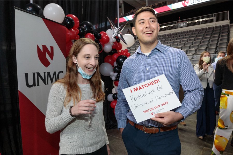 A man and woman pose for a photo. The man holds a sign reading "I matched! Pathology @ University of Massachusetts, Match Day 2022"