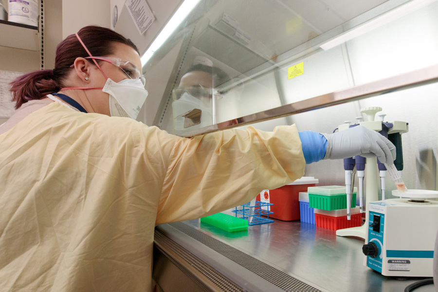 A student wearing personal protective equipment works in a lab