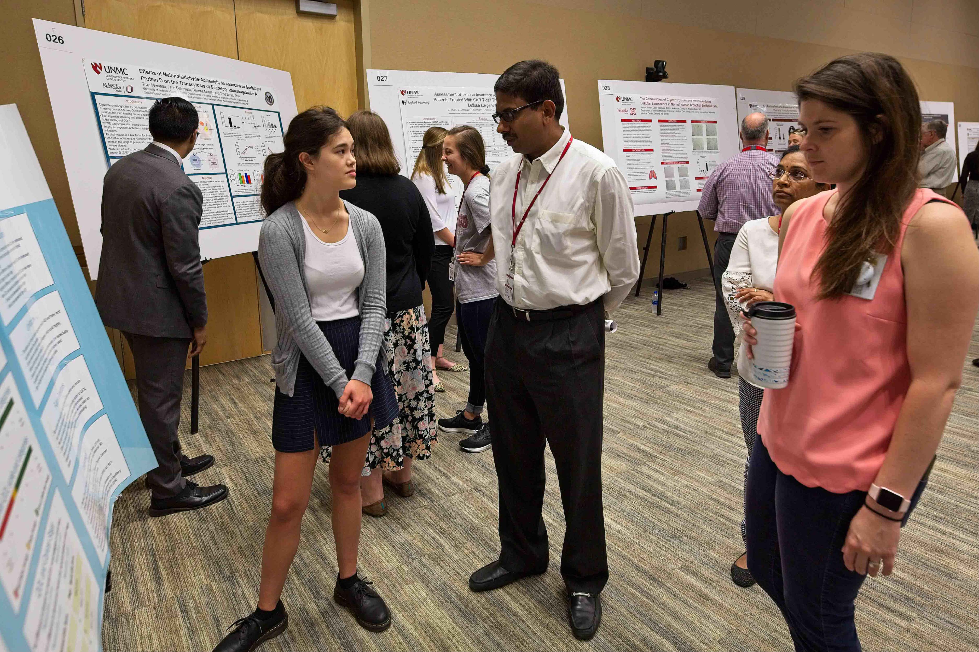 A student presents information on a research poster to observers