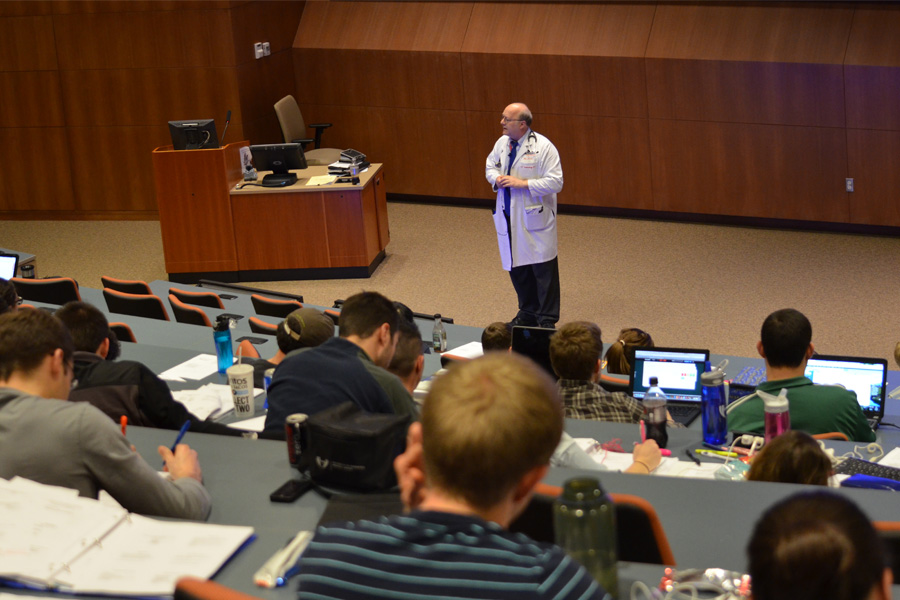 A professor teaches in front of students in a lecture hall