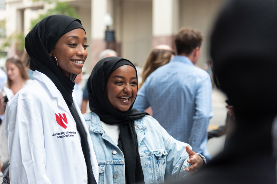 Two students pose for photos wearing white coats