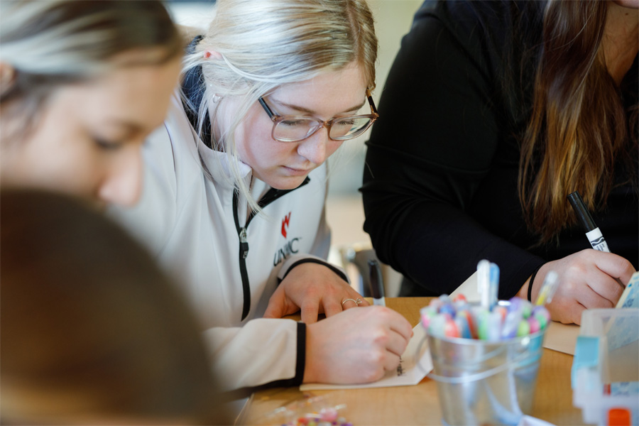 Students sitting at a table make cards with arts and crafts supplies