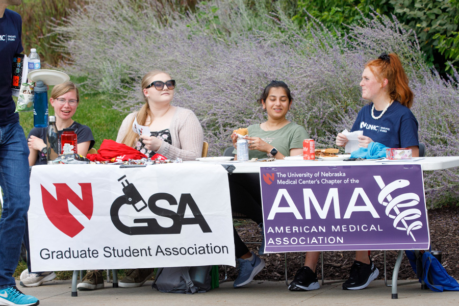 Students sit at a table with banners for the Graduate Student Association and the American Medical Association