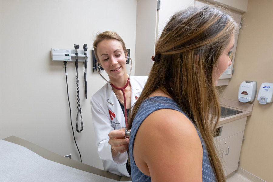 A medical student listens to a patient's lungs