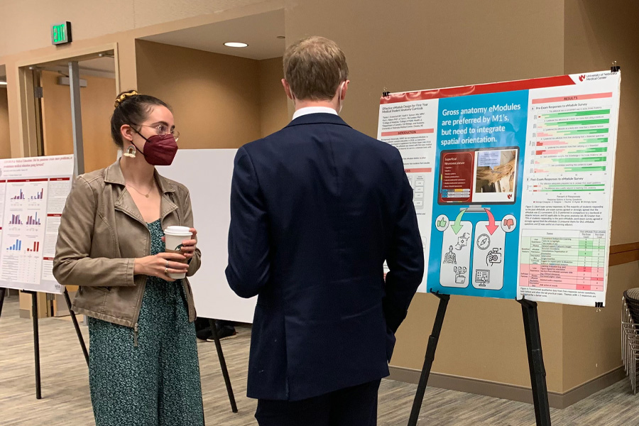 A student talks about a research poster to an onlooker