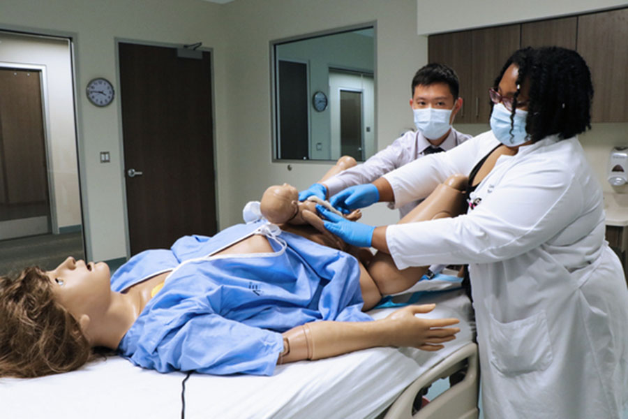 Students practice delivering a baby using a manikin in a simulation suite.