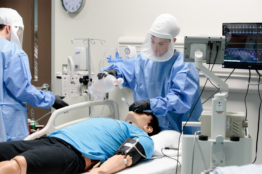 Residents work with a mannequin while dressed in personal protective equipment