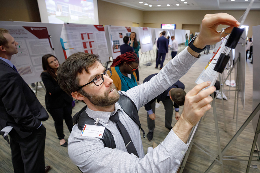 Internal Medicine/Pediatrics resident puts up poster at the GME Annual Research Symposium.