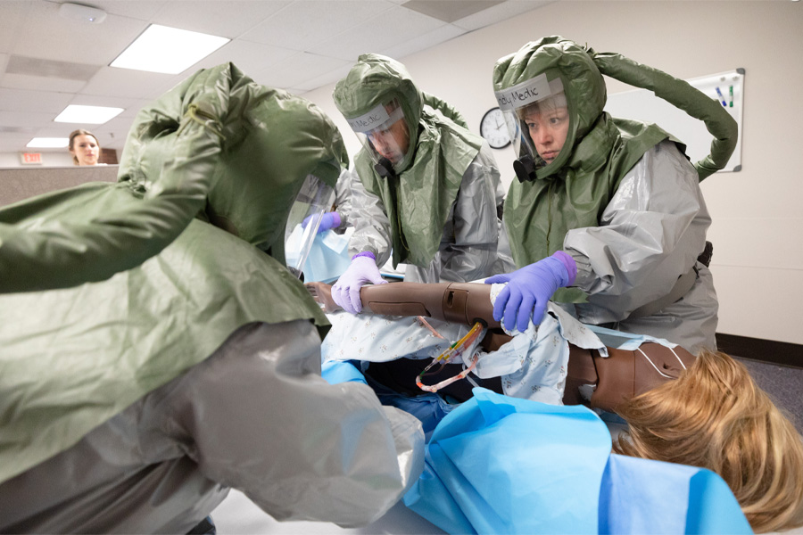 Health care workers in personal protective equipment work with a mannequin