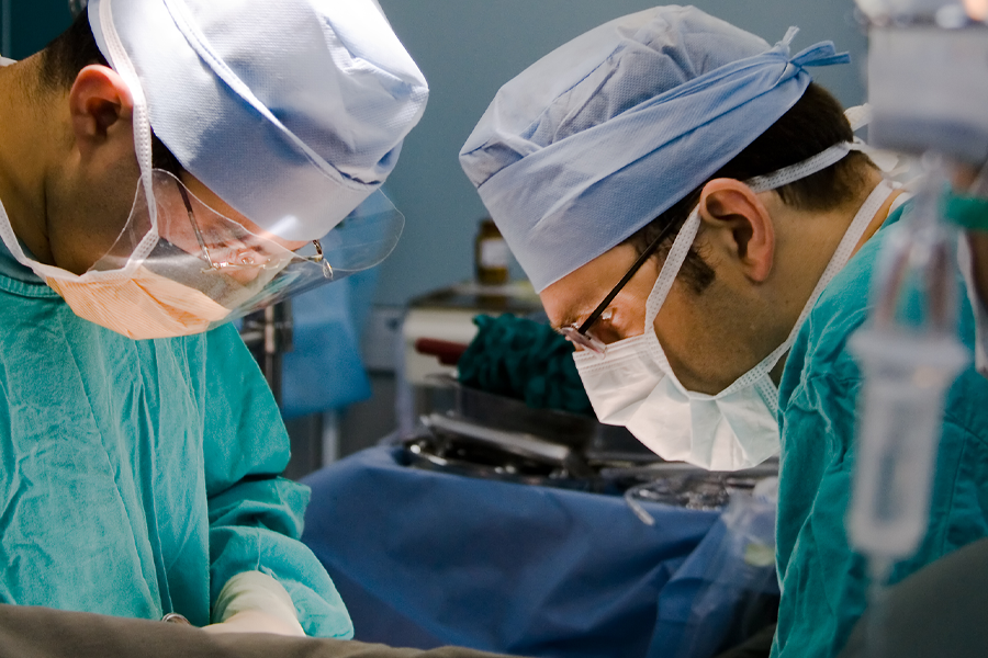 Two neurosurgeons bend over a surgery table