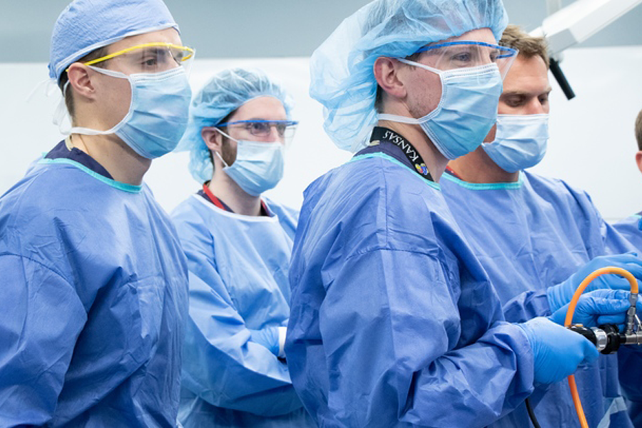 A group of students wearing personal protective equipment observe a training