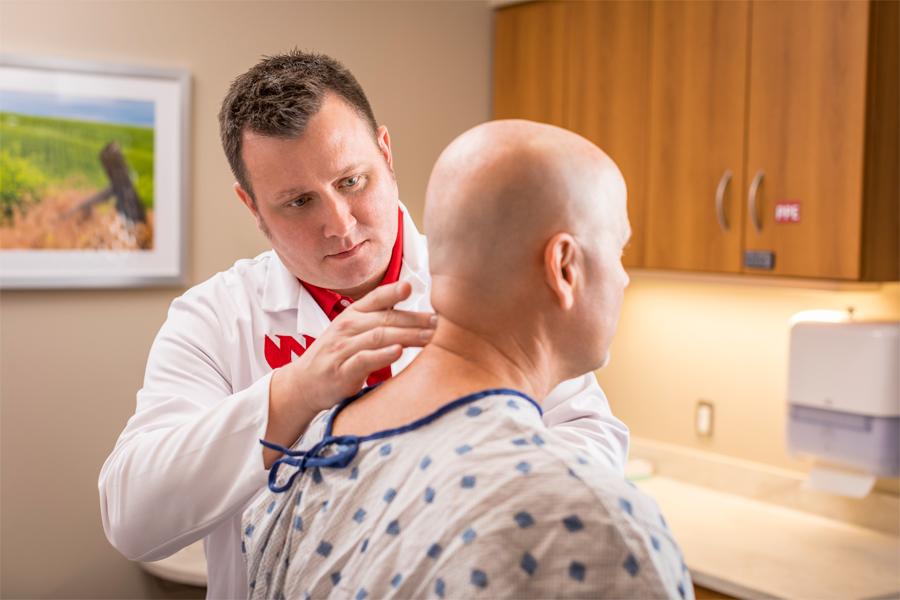 A physician examines the back of a patient's neck