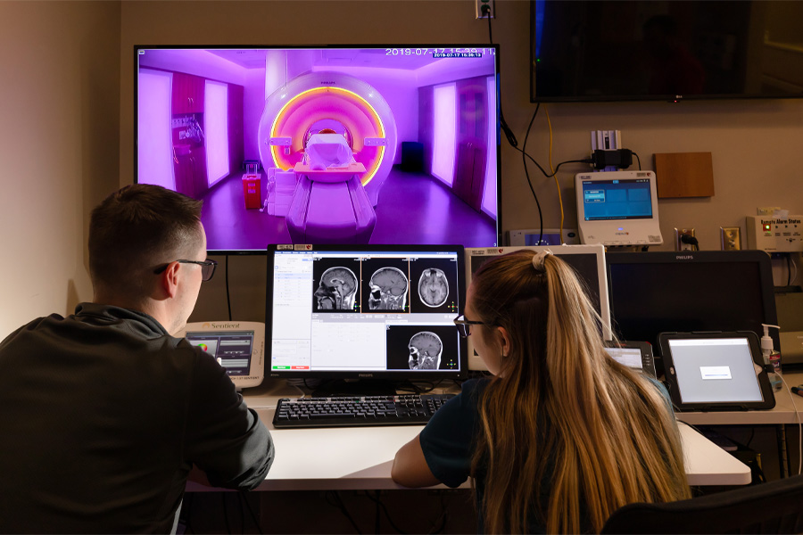 Two health care workers examine scans on a computer
