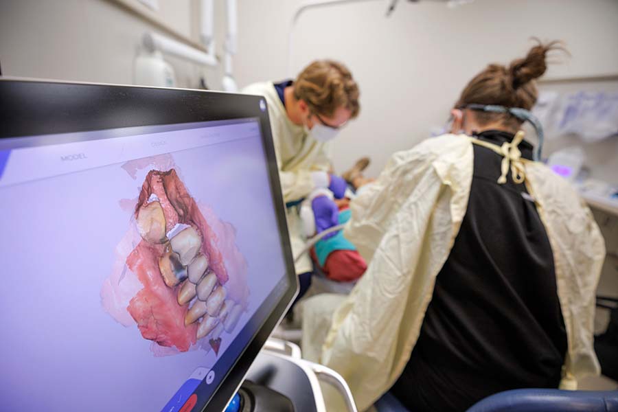A simulator of a set of teeth is seen in front of a faculty member working with a student in a clinical setting.