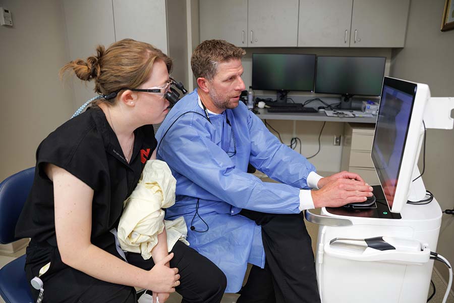 A faculty researcher works with a s student on a computer.