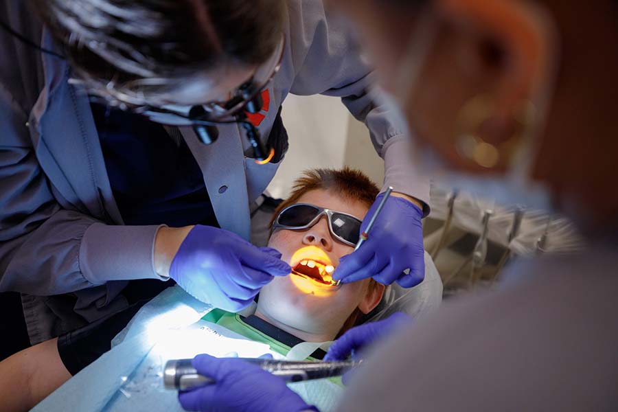 A student examines the teeth of a young patient.