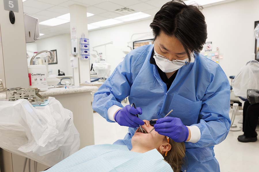 A male resident examines a patient in the College of Dentistry clinic.