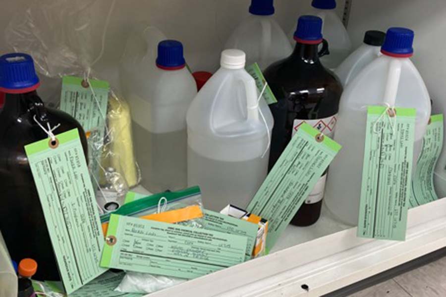 Tagged and labeled containers of chemical waste await pick-up.