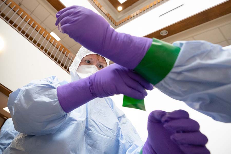 During a training session, two employees learn the proper method of donning of PPE.