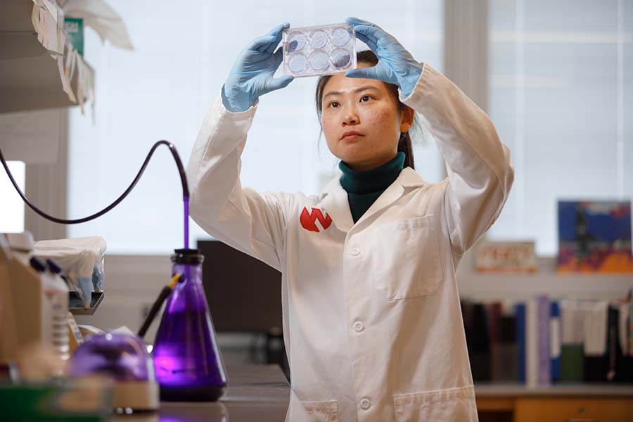 A UNMC faculty member holds up samples to study them in a laboratory.