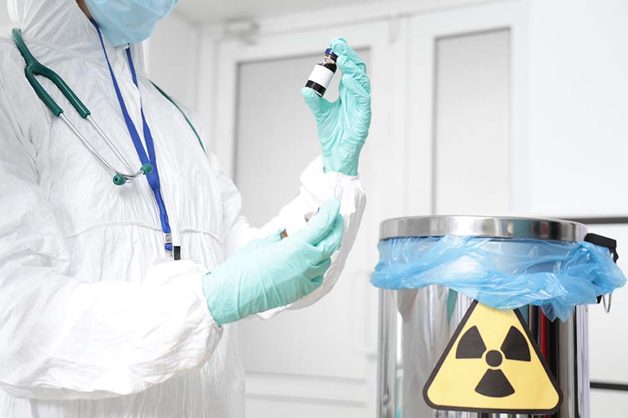 A worker holds a vial of radioactive material.