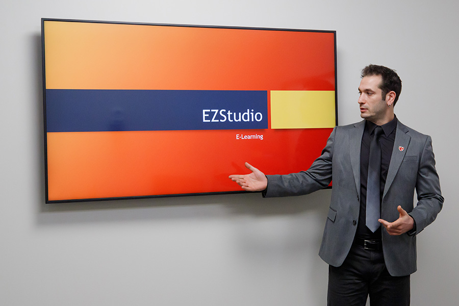 Man stands in front of monitor in studio to demonstrate how to use the presentation mode.