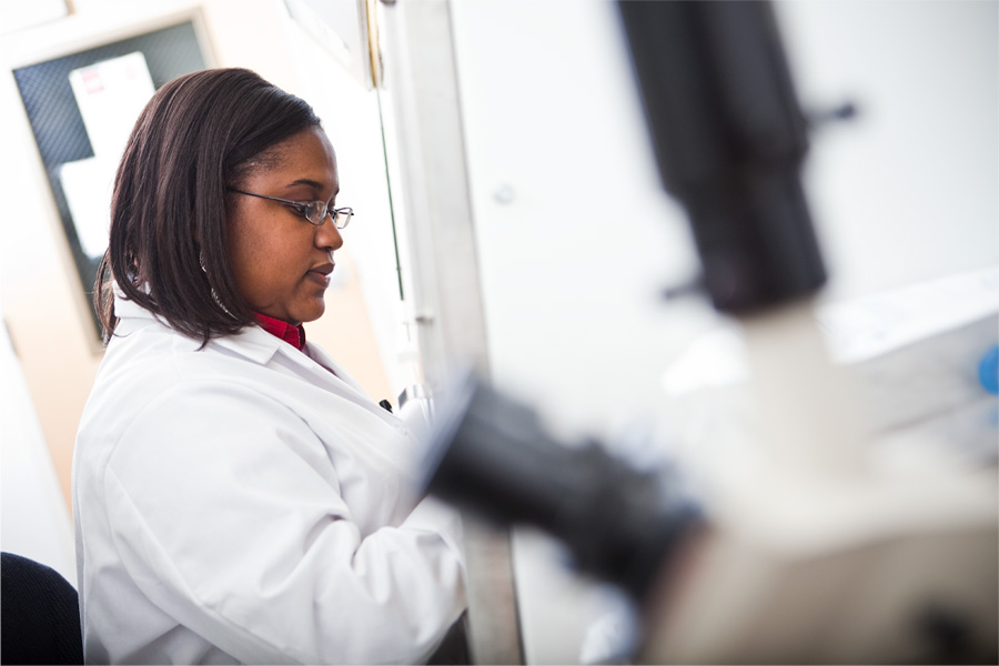 A woman in a white lab coat works in a lab