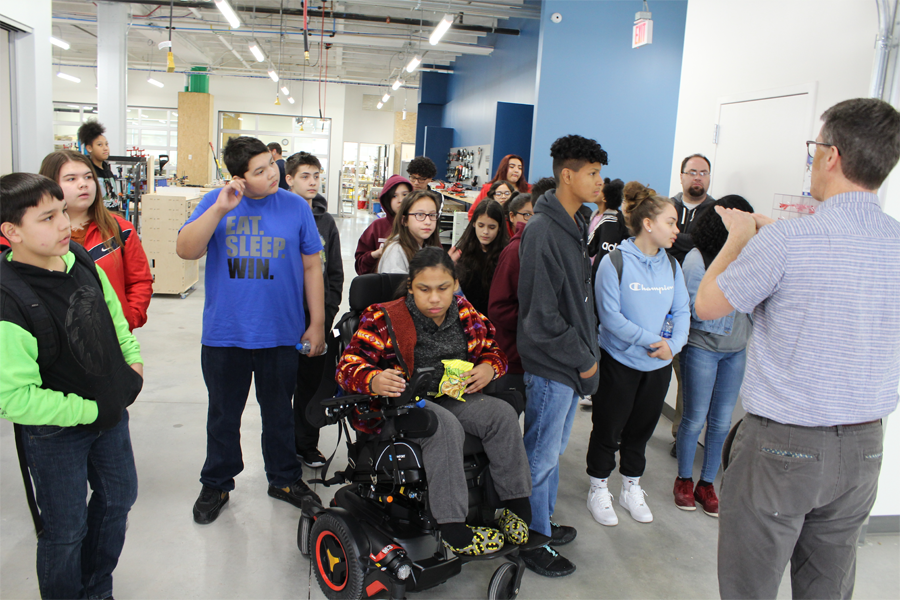 Middle school students listen to a tour guide in a science facility