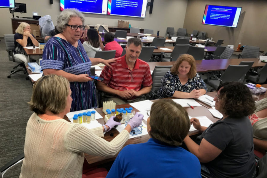 Middle and high school teachers sit around a table at an educational workshop