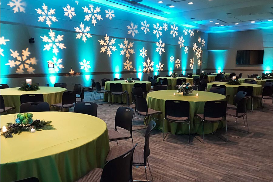 The Events Center transformed for a holiday party with dramatic snowflake lighting on the walls.