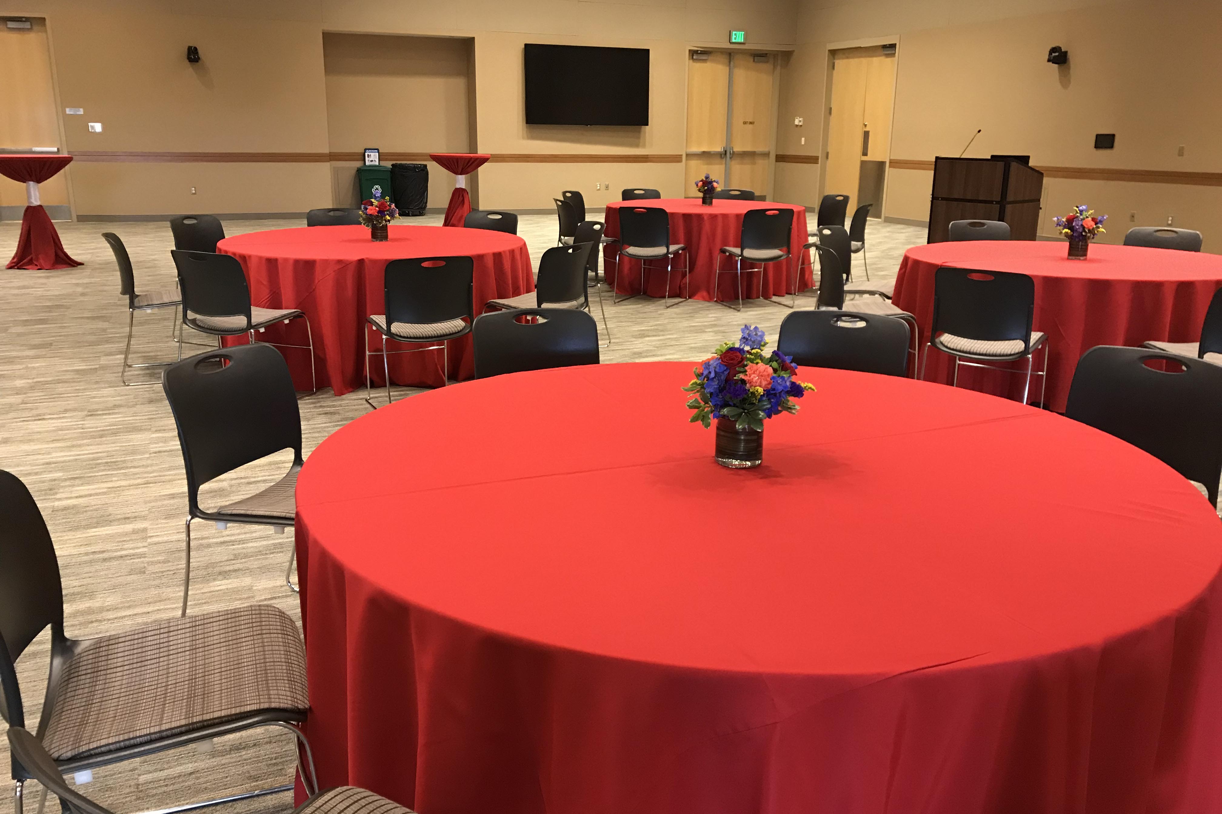 A beautiful reception in the Events Center with red linens and colorful floral centerpieces.