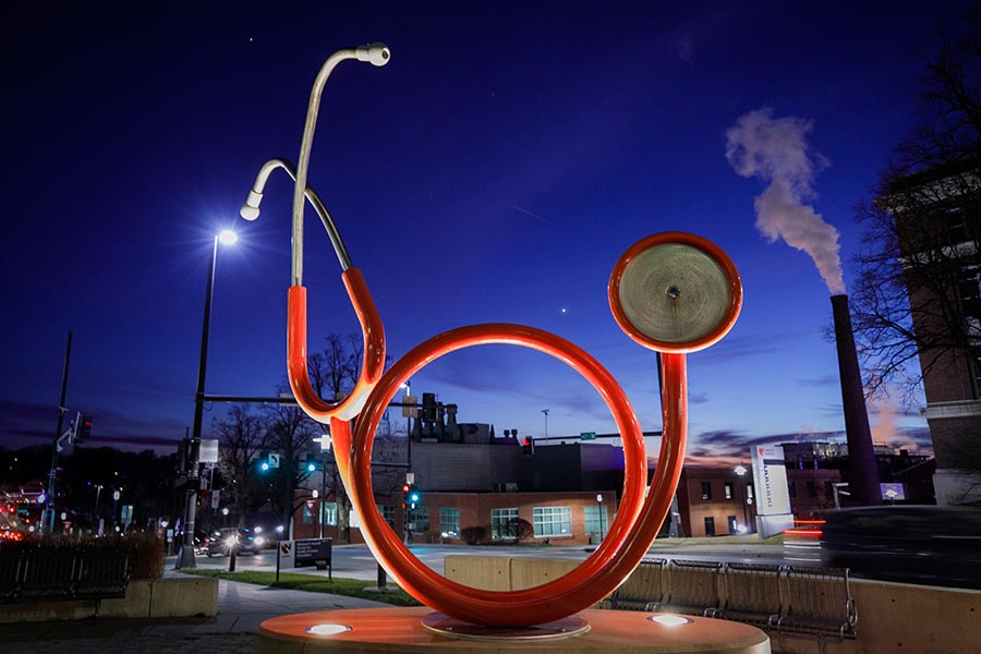 The red, stethoscope sculpture outside of the Sorrell Center lit up at night.