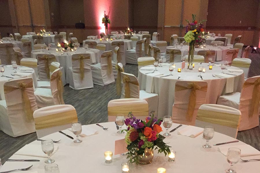The Events Center set for a reception with white linens and colorful floral centerpieces.