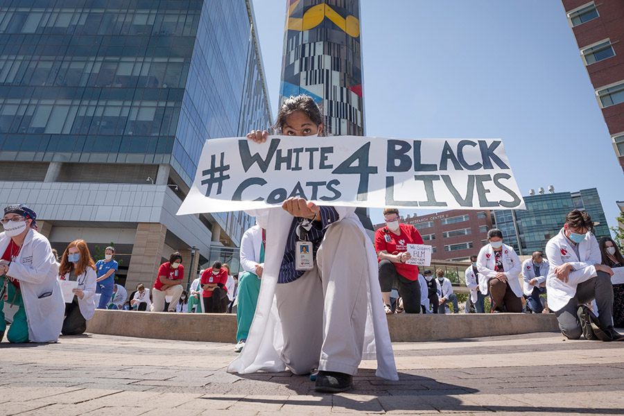 UNMC employees kneel outside the Buffett Cancer Center for White Coats for Black Lives.