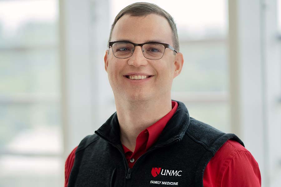 man with glasses red shirt and black fleece vest