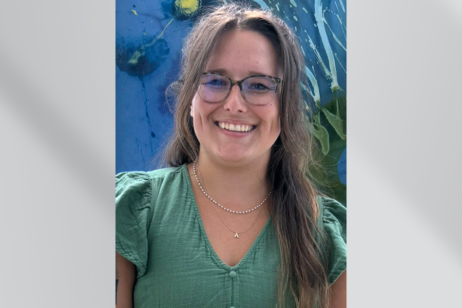 woman with long brown hair and glasses in green shirt