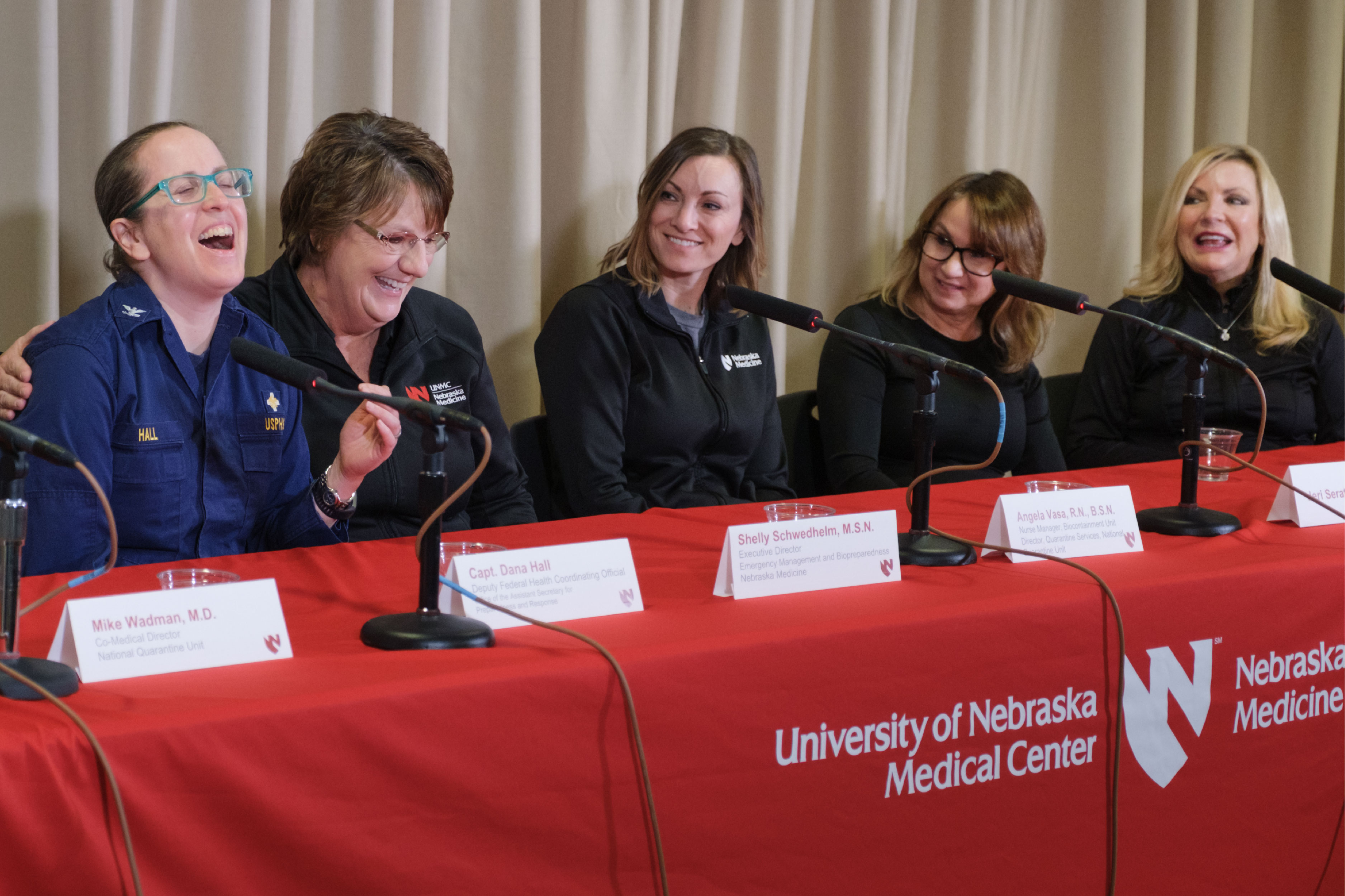 Five women speak in a conference setting