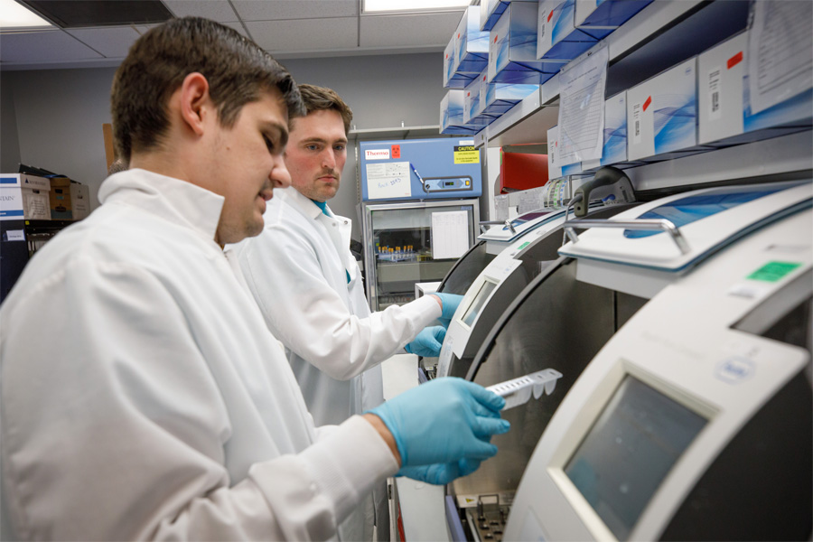 Two men in white coats consult results on a machine