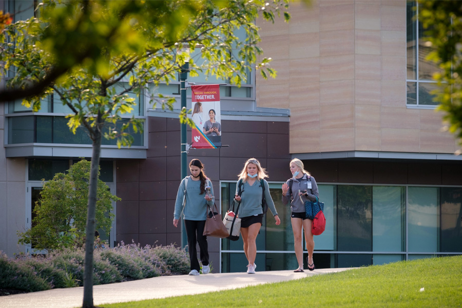 Three women walk outdoors on UNMC's Omaha campus.