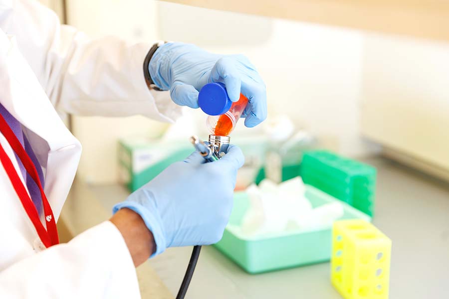 Gloved hands working with lab equipment.