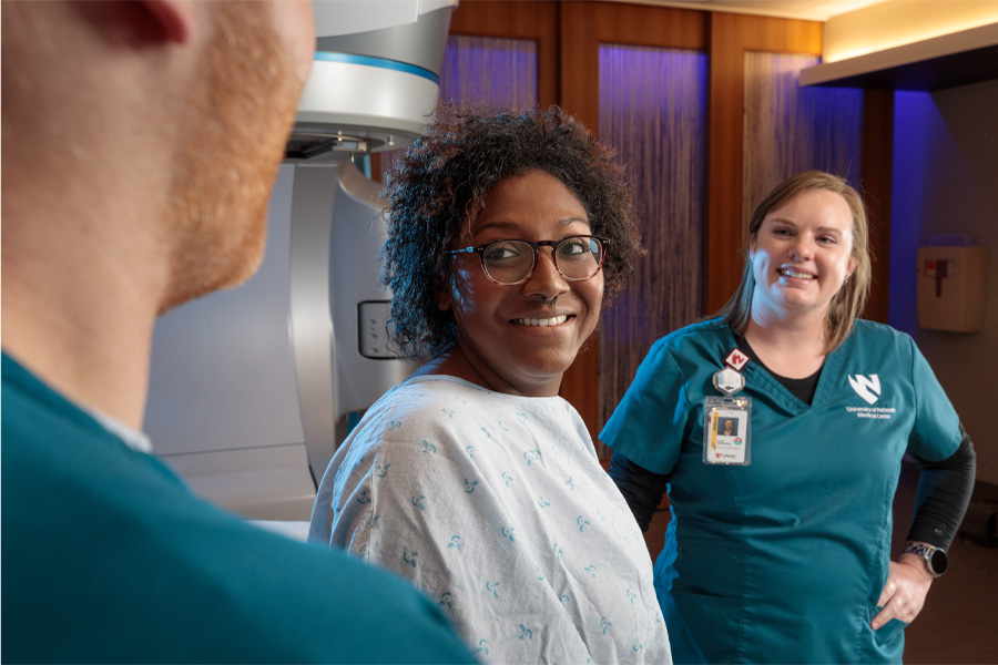 A woman smiles at two heath care providers