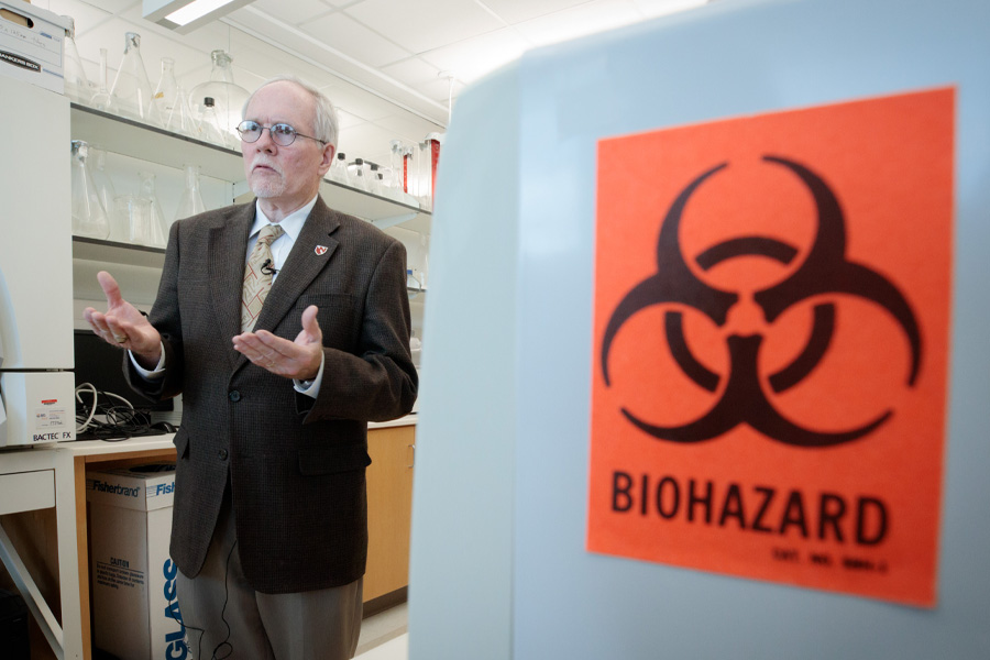 A man stands near a piece of equipment with a "Biohazard" sign