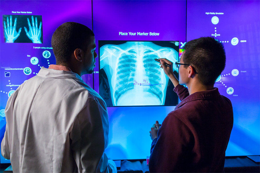 Two students consult a digital screen