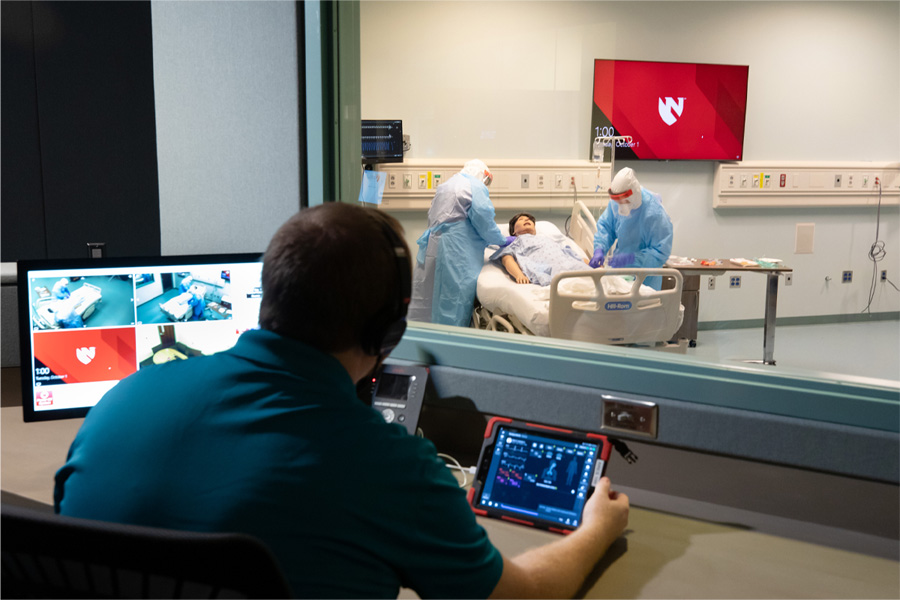 An observer watches health care professionals through a window